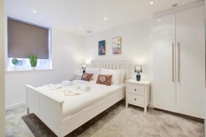 a white bedroom with a large white bed and a window at Elegant 1 Bedroom Flat in Brentwood