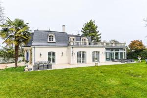 a large white house with a balcony on top of a yard at Villa Sweet Birds in Noisy-le-Grand