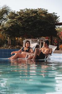 three people in bathing suits sitting in a swimming pool at La Triada in Ríohacha