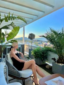 a woman sitting in a chair on a balcony at One 360 Skyline Athens Penthouses in Athens