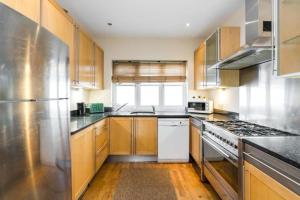 a kitchen with stainless steel appliances and wooden cabinets at Comfortable Family Villa in London