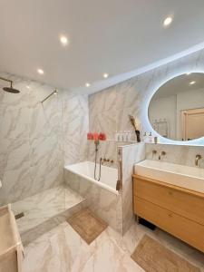 bagno con vasca, lavandino e specchio di Le Clara Chic - 1 Chambre - Balcon - 4 Personnes - Cosy a Boulogne-Billancourt