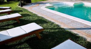 ein Schwimmbad mit zwei Bänken im Gras neben einem Pool in der Unterkunft Ferienwohnung für 4 Personen ca 70 m in Giungano, Kampanien Cilento in Giungano