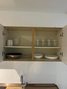 a kitchen cabinet with plates and bowls on it at Apartments zum Wildgehege in Siegen