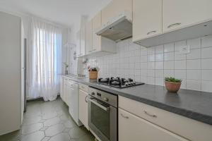 La cuisine est équipée de placards blancs et d'un four avec plaques de cuisson. dans l'établissement Appartement spacieux avec hamac + parking gratuit, à Gentilly
