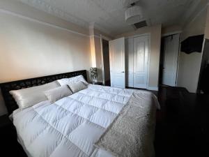 um quarto com uma grande cama branca com almofadas brancas em GEM of a Free-Standing Family House in Great Neighborhood em Brooklyn