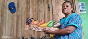 une femme debout à côté d'un panneau avec des fruits sur celui-ci dans l'établissement Lodging and Adventure, à Soposo