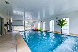 a large swimming pool with blue water in a building at Villa Sweet Birds in Noisy-le-Grand