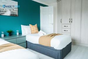 sypialnia z 2 łóżkami i zieloną ścianą w obiekcie Elegant 3 bed apartment Luton w Luton