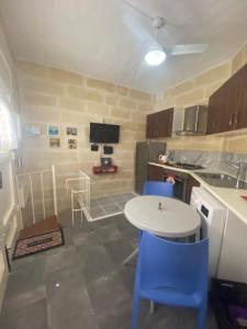 a kitchen with a white table and blue chairs at Birgu Studio Maisonette in Birgu