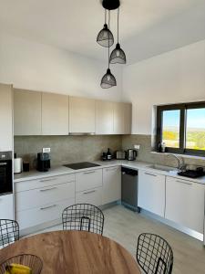 a kitchen with white cabinets and a table and chairs at Villa Elaia in Sitia
