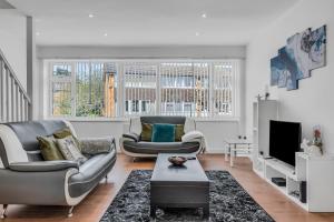 uma sala de estar com duas cadeiras e uma televisão em Relaxed Home em Eltham