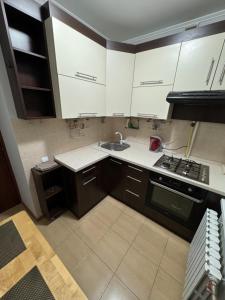 uma cozinha com armários brancos e um lavatório em Apartament Chișinău Botanica em Chisinau