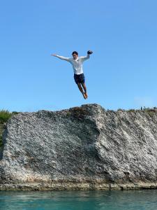 Ein Mann springt von einem Felsen ins Wasser in der Unterkunft Paradise Cove home in Gregory Town