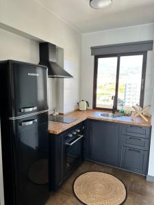 eine Küche mit einem schwarzen Kühlschrank und einer Spüle in der Unterkunft Aloha Playa España in Benalmádena