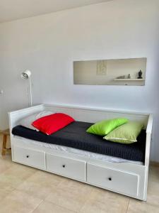 a white bed with two colorful pillows on it at Casa Nemo Cotillo Mar in El Cotillo