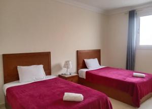 1 dormitorio con 2 camas con sábanas rojas y ventana en Giza Home, en El Cairo