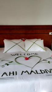 un letto con due cuscini con le parole welcomeanananan di AHI Maldives a Omadhoo