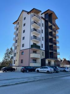 兹拉蒂博尔West Residence - Panorama lux & Spa的一座高楼，停车场里停满了汽车