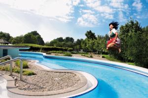 a woman is jumping into a swimming pool at Ferienwohnung Majo in Bad Birnbach
