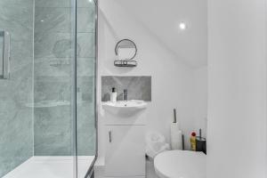 uma casa de banho branca com um chuveiro e um lavatório. em Relaxed Home em Eltham