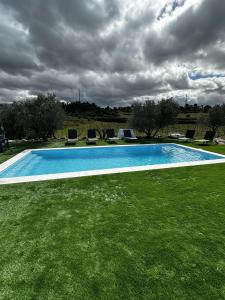 een zwembad in een grasveld met stoelen bij Quinta de Gandarem in Torre de Moncorvo