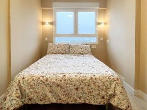1 dormitorio con 1 cama con colcha de flores y ventana en Acogedor y moderno apartamento, en Zamudio