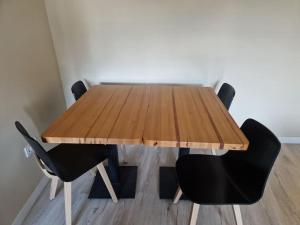 une table en bois entourée de deux chaises noires dans l'établissement Acogedor y moderno apartamento, à Zamudio