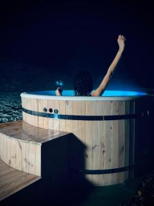 a person in a hot tub in the water at night at Bies-Czaderskie Chaty in Ustrzyki Dolne
