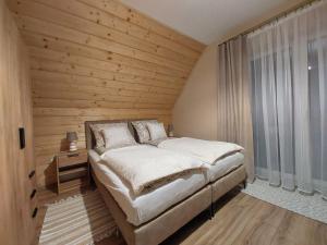 a bedroom with a bed and a wooden wall at Agroturystyka Bliżej Natury in Rymanów-Zdrój