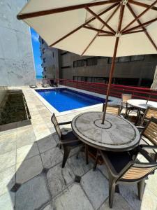 a table and chairs with an umbrella next to a pool at NAVEGANTES HOTEL VISTA PARA MAR Boa Viagem in Recife