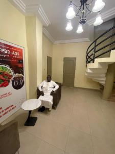 バマコにあるAppartement Bamako ACI 2000の待合室の椅子に座る男 +2枚の写真