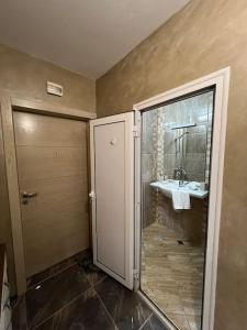 ein Bad mit einer Dusche, einem Waschbecken und einer Tür in der Unterkunft Tei-Zi apartments in Burgas City