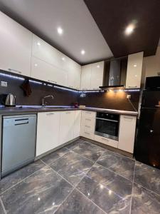 a kitchen with white cabinets and a black refrigerator at Tei-Zi apartments in Burgas City