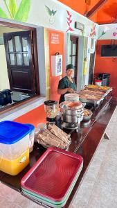 un hombre parado detrás de un mostrador en una cocina con comida en hotel villa nazareth, en Quimbaya