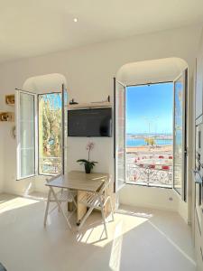 un soggiorno con un tavolo e una grande finestra di MENTON # MONACO - F1 GP - 4 PERSONS - SEA VIEW - NEW - PARKING - CLIM - PREMIUM - BEACH and SUN a Mentone
