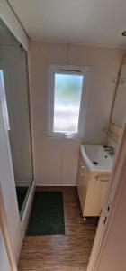 een kleine badkamer met een wastafel en een raam bij Mobil-home de vacances in Le Bosc
