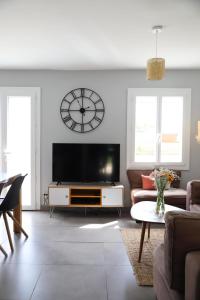 een woonkamer met een tv en een klok aan de muur bij Maison - 3 chambres - Jardin in Huisseau-sur-Cosson