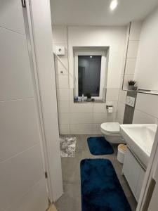 a bathroom with a toilet and a sink with blue rugs at Fewo am Tillysee in Wardenburg in Wardenburg