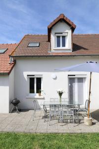 een wit huis met een tafel en stoelen en een parasol bij Maison - 3 chambres - Jardin in Huisseau-sur-Cosson