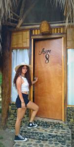 a woman in a hat standing in front of a door at Hostal Zirumake Dentro del Parque Tayrona in El Zaino
