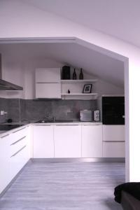a white kitchen with white cabinets and appliances at La dimora in Borgo San Dalmazzo