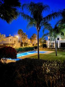 uma piscina à noite com palmeiras e edifícios em Casa Mila Roda Golf Resort Murcia em Roda