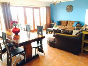 a living room with a table and a couch at Helderberg Guesthouse in Gordonʼs Bay