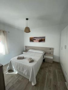 a white bedroom with a bed and a pendant light at Doamvid Universidad in Ciudad Real