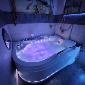 bañera blanca en una habitación con luces en GDAŃSK by the Sea - PRESTIGE HOME SPA Apartments with a luxurious JACUZZI, SAUNA and an exclusive Massage Chair available in one of the apartments!, en Gdansk