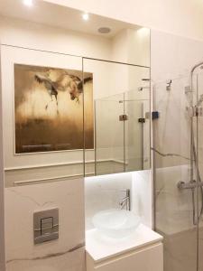 uma casa de banho com um lavatório e uma pintura na parede em Glamour Apartment Sopot em Sopot