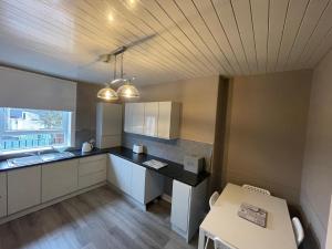 a kitchen with white cabinets and a table and a ceiling at Gateway to the Loch in Balloch