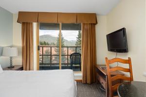 pokój hotelowy z łóżkiem i dużym oknem w obiekcie Cascade Lodge w mieście Whistler