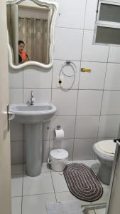 a man taking a picture of a bathroom with a sink and toilet at Bela vista Rio in Porto Alegre